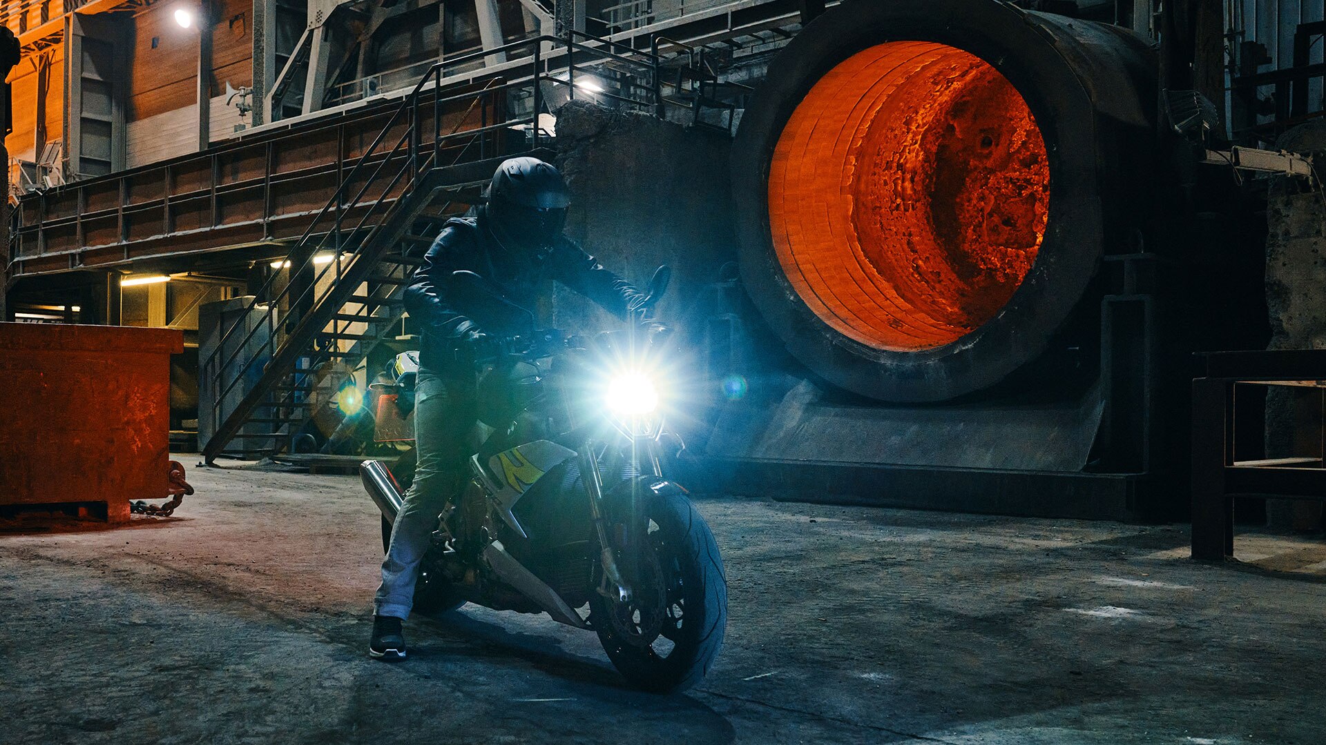 Vediamo la S 1000 R nei leggendari colori M che passa davanti a un muro in cemento.