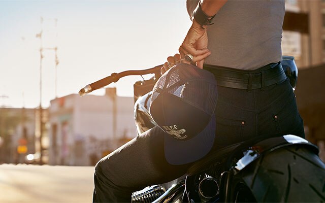 Nella foto di dettaglio, una motociclista tiene in mano il cappellino Boxer della collezione e indossa i jeans RoadCrafted da donna.