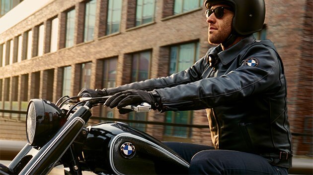 Un motociclista è seduto con disinvoltura sulla moto e indossa la giacca in pelle FlatTwin da uomo.